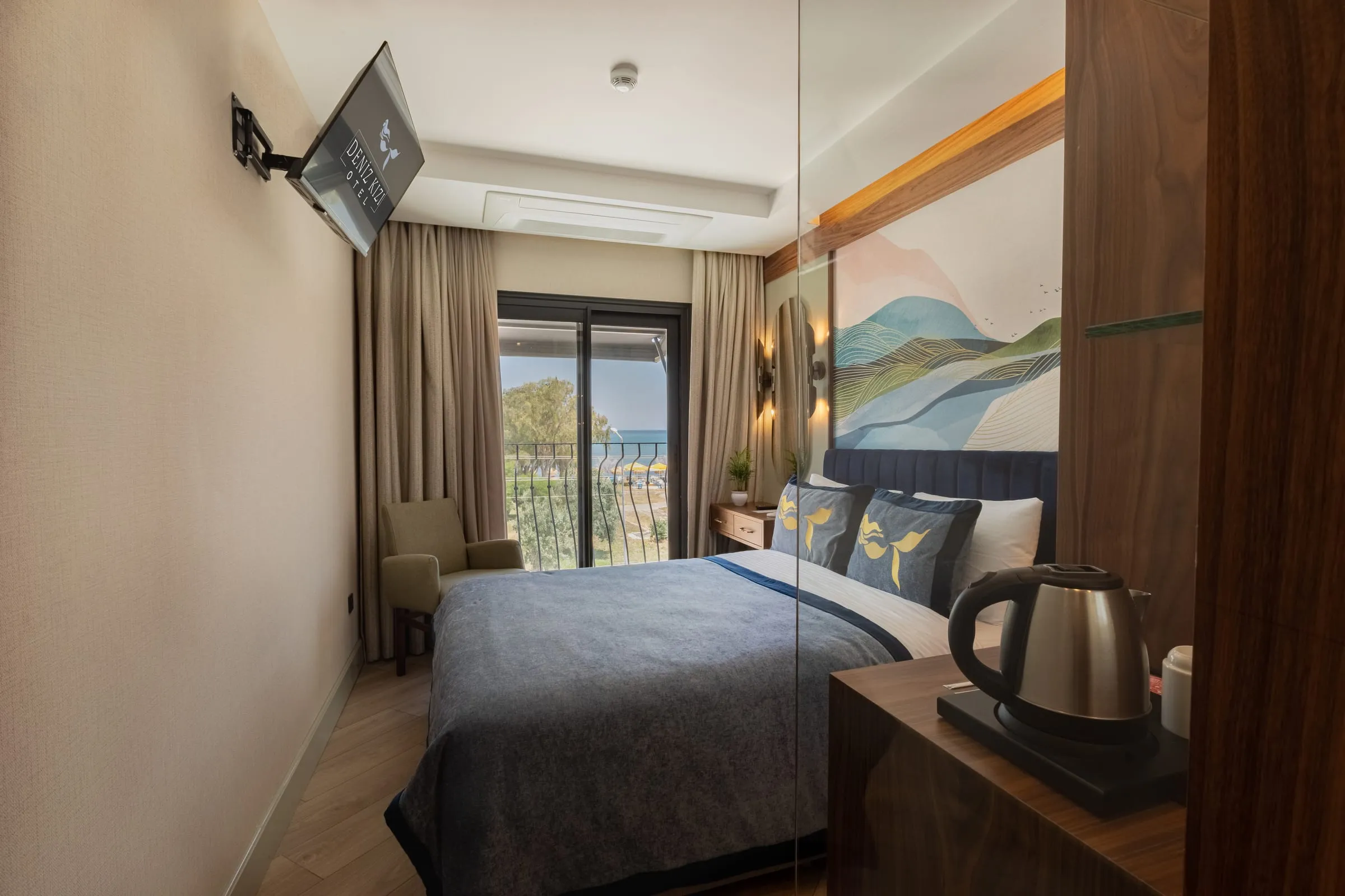 The mirrored wardrobe wall reflects the room; a television on the wall, a kettle and cups on the wooden console